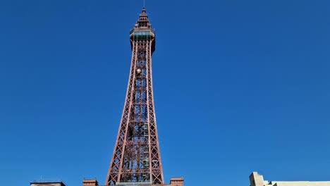 Blackpool-tower-pan-up-from-comedy-street-art-at-the-bottom-of-seaside-town-promenade,-Looking-up