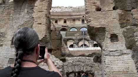 Turista-Masculino-Tomando-Fotos-Por-Teléfono-De-Ladrillos-De-Los-Túneles-Subterráneos-En-El-Coliseo-De-Roma-En-Cámara-Lenta