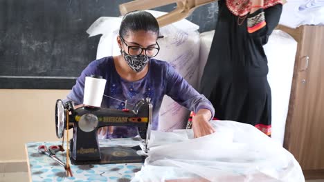 Front-view-of-a-young-Indian-girl-operating-a-sewing-machine-to-earn-her-living,-the-precision-and-skill-she-is-doing