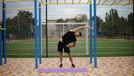 Longitud-Completa-De-Un-Apuesto-Joven-Deportista-Barbudo-En-El-Estadio-Calentando,-Estirándose,-Haciendo-Curvas-Laterales