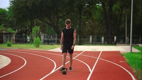 Ein-Mann-In-Schwarzer-Sportkleidung-Mit-Einer-Wunderschönen-Körperskulptur-Trainiert-Mit-Gewichten.-Im-Freien-In-Der-Nähe-Des-Stadions