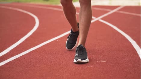 Imágenes-De-Cerca-De-Las-Piernas-De-Un-Hombre-Con-Zapatillas-Negras-Vienen-A-Entrenar-Con-Peso-Bob-Al-Aire-Libre-En-La-Pista-De-Carreras-Al-Aire-Libre-En-Cámara-Lenta