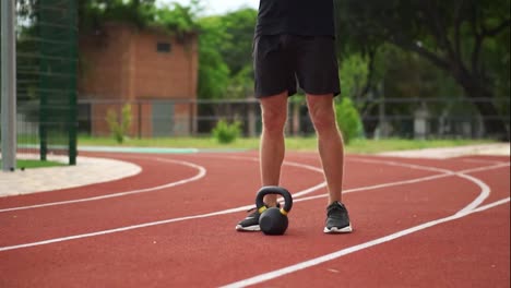 Close-up-footage-of-a-man's-legs-in-black-sneakers-standing-in-front-weight-bob-outdoors-on-the-racetrack