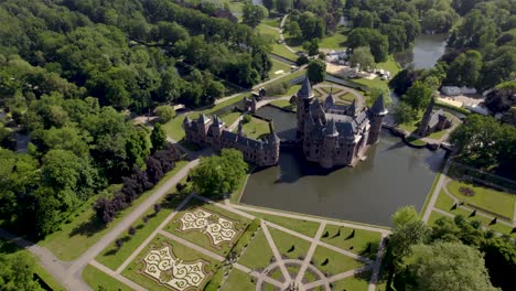 Backwards-movement-aerial-revealing-historic-picturesque-castle-Ter-Haar-in-Utrecht-with-typical-towers-and-fairy-tale-cants-facade-exterior-on-a-bright-day-with-landscaping-gardens-in-the-foreground