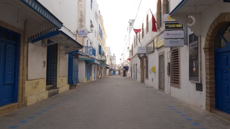 Caminando-Por-Una-Calle-Estrecha-Y-Vacía-En-Una-Ciudad-De-Arquitectura-Azul-Y-Blanca,-Essaouira,-Marruecos