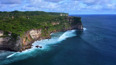 Breathtaking-View-Of-Pura-Uluwatu-Temple-By-Cliffside-In-Distance-With-Relaxing-Ocean-View-In-Bali,-Indonesia