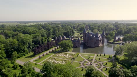 Langsam-Rotierende-Luftaufnahme-Zeigt-Das-Historische-Malerische-Schloss-Ter-Haar-In-Utrecht-Mit-Typischen-Türmen-Und-Märchenhafter-Fassade-An-Einem-Hellen-Tag-Mit-Landschaftsgärten-Im-Vordergrund