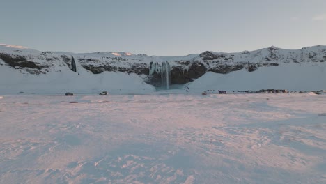 Luftlandschaftsansicht-Eines-Schneebedeckten-Winterpanoramas-über-Dem-Wasserfall-Seljalandsfoss-In-Island-In-Der-Abenddämmerung