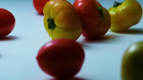 Tomates-Rojos,-Verdes-Y-Amarillos-Ruedan-Sobre-La-Mesa,-Cámara-Lenta