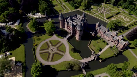 Rotierende-Luftaufnahme,-Die-Das-Historische,-Malerische-Schloss-Ter-Haar-In-Utrecht-Mit-Typischen-Türmen-Und-Märchenhafter-Fassade-An-Einem-Hellen-Tag-Mit-Landschaftsgärten-Im-Vordergrund-Zeigt