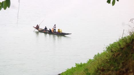A-group-of-village-people-sat-on-a-small-wooden-boat-crossing-a-river