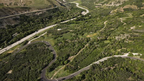Un-Dron-Se-Inclina-Sobre-La-Carretera-Del-Cañón-De-Provo-Con-Las-Montañas-Wasatch-A-Los-Lados