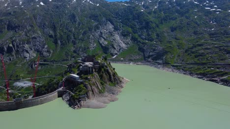 Aerial-drone-zoom-in-shot-over-Hotel-Grimsel-Hospiz-in-Grimsel-Pass,-Swiss-Mountain-in-Switzerland-on-a-sunny-day