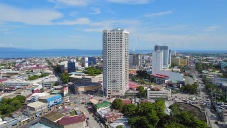 Modern-High-Rise-Tower-Residence-Building-Surrounded-By-Urban-Area-With-Ocean-In-The-Background