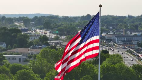 Hoch-Aufragende-Amerikanische-Flagge,-Die-Sich-Sanft-Im-Wind-Bewegt,-Grüne-Vorstadtkulisse