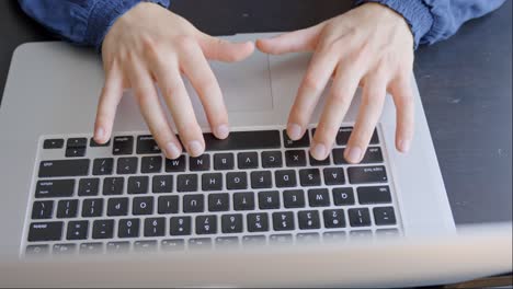 Female-hands-of-typing-on-laptop-keyboard-at-home-desk,-above-view