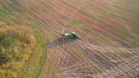 Filmische-Luftaufnahme-Der-Landwirtschaft-Eines-Traktors,-Der-Auf-Einem-Großen-Feld-Arbeitet