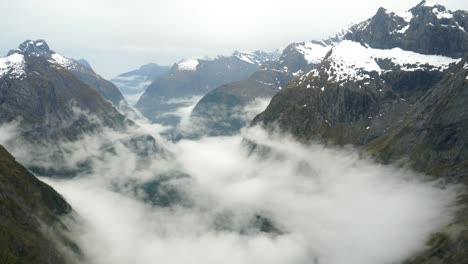 Nature-timelapse-shot-capturing-the-wilderness-landscape-of-Gertrude-Saddle-trail-on-Fiordland-National-Park-with-dramatic-cloud-formation-between-the-rocky-valley-during-cold-and-snowy-winter-season