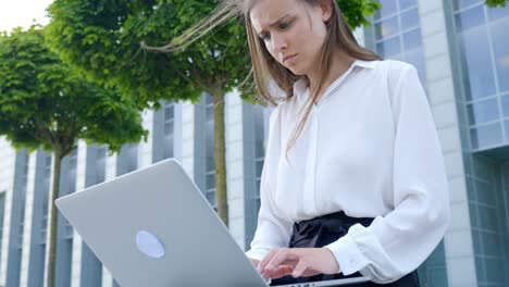 Confused-and-focused-business-woman-working-with-laptop-outdoors