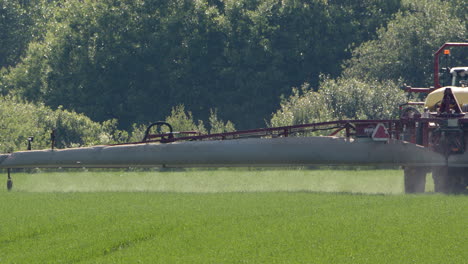 Pulverizador-Agrícola-Tirado-Por-Tractor-Rociando-Pesticidas-En-Cultivos,-Tele-Shot