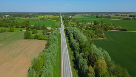 Drohnen-Rückwärtszoom-Einer-Ländlichen-Bauerngemeinde-Mit-Fahrzeugen,-Die-Auf-Einer-Das-Land-Teilenden-Autobahn-Durchfahren