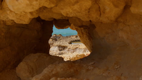 Looking-Into-The-Hole-At-The-Sandstone-Cliffs-At-Praia-do-Evaristo-Beach-In-Albufeira,-Algarve,-Portugal