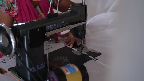 close-up-scene-of-an-Indian-woman-wearing-a-mask-over-her-face-sewing-with-both-hands-by-a-machine,-making-a-good-living-by-doing-this-sewing