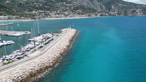 Breakwater-for-Marina-at-Menton-southern-France-with-lighthouse-at-the-end,-Aerial-dolly-in-shot