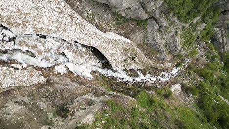 Downward-drone-flight-over-the-melting-ice-and-snow-of-the-avalanche-in-Provo-Canyon,-Utah