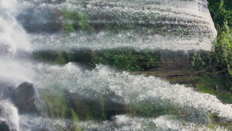 Twin-waterfall,-slow-motion-falling-water-onto-rocks-in-green-lush-vegetation