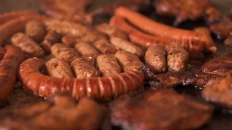 Closeup-shot-of-smoking-sausages,-cevapi-and-chuck-meat-in-lard---cooking-in-slow-motion,-trucking-shot