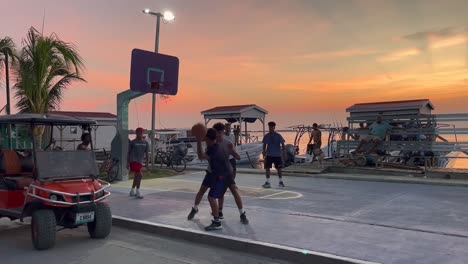 Kinder-Spielen-Basketball-Auf-Einem-Platz-Am-Meer-Bei-Sonnenuntergang-In-San-Pedro,-Belize