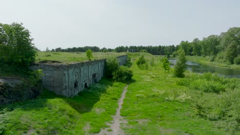 Aerial-establishing-view-of-abandoned-historical-concrete-seaside-fortification-buildings,-Southern-Forts-near-the-beach-of-Baltic-sea-in-Liepaja,-sunny-summer-day,-ascending-drone-shot-moving-forward