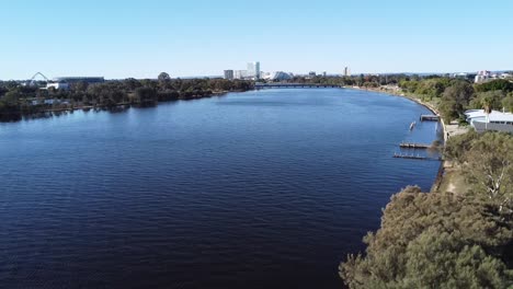 Drone-shot-descending-with-view-of-Optus-Stadium,-Crown-Casino-Burswood-and-Swan-River-down-to-paperbark-tree-in-Perth,-Western-Australia