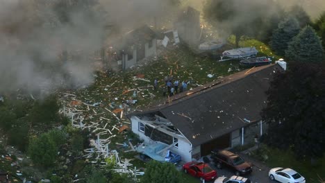 Destroyed-Houses-after-Gas-Leak-Explosion-in-American-Neighborhood-Aerial-Drone-Panoramic-View,-People-Observe-Smoke-and-Blown-Up-Buildings
