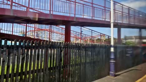 Blick-Aus-Dem-Fenster-Des-Zuges,-Der-In-Den-Bahnhof-Blackpool-Einfährt-Und-Die-Achterbahn-Des-Vergnügungsparks-Sieht