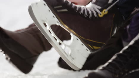 Close-shot-putting-on-and-lacing-up-ice-skates-outdoors-in-the-snow
