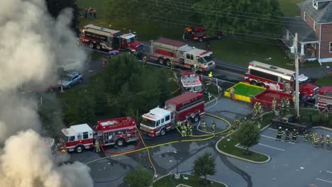 Many-firefighting-vehicles-responding-to-massive-fire-due-to-propane-leak-explosion,-Aerial-shot
