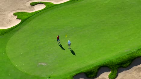 Der-Golfspieler-Macht-Einen-Kurzen-Putt-Auf-Einem-Wunderschönen-Grün-Mit-Umliegenden-Bunkern