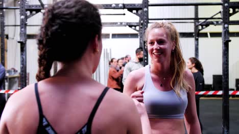 Beautiful-Caucasian-women-in-sportswear-greet-each-other-in-crossfit-gym