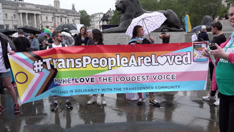 Menschen-Halten-Ein-Transparent-Mit-Der-Aufschrift-„Trans-Menschen-Werden-Geliebt,-Liebe-Ist-Die-Lauteste-Stimme“,-Während-Sich-Demonstranten-Am-Trafalgar-Square-Versammeln,-Um-Sich-Auf-Den-Marsch-Zum-London-Trans-Pride-2023-Vorzubereiten