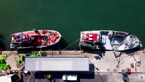 Top-view-of-commercial-fishing-boats-being-unloaded-at-harbor,-timelapse
