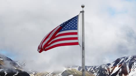 An-American-flag-waves-in-the-breeze-in-front-of-Alaskan-mountains-in-slow-motion