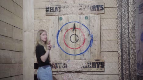 Young-blonde-Female-throwing-an-axe-at-a-target-from-above-her-head