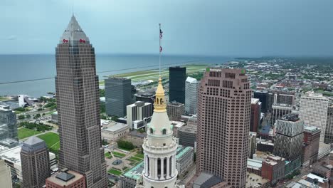 Luftaufnahme-Der-Türme-Der-Innenstadt-Von-Cleveland,-Ohio,-USA-Und-Der-Wehenden-Amerikanischen-Flagge-Auf-Den-Terminal-Tower-Residenzen,-Hochhaus-Drohnenaufnahme-Im-Orbit