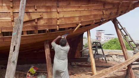 Artisan-Using-Saw-On-Wooden-Hull-In-Dry-Dock-At-Ibrahim-Hyderi