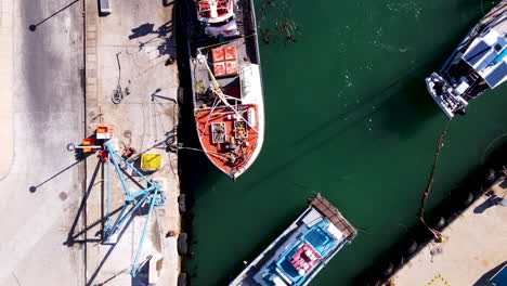 Drone-top-down-dolly-over-moored-commercial-fishing-vessels-at-harbor