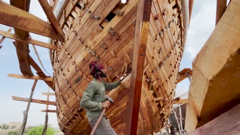 Male-Ship-Builder-Using-Hammer-And-Chisel-On-Front-Keel-On-Wooden-Hull