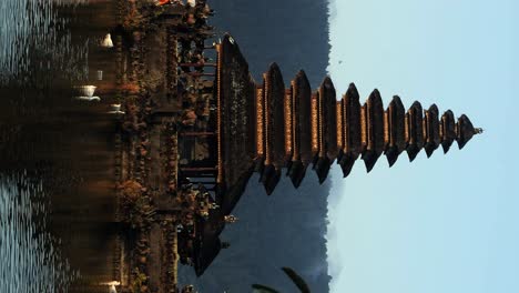 Vertikale-Enthüllungsaufnahme-Von-Pura-Segara-Ulun-Danu,-Einem-Spirituellen-Tempel-Im-Wasser-Auf-Bali-Mit-Reflektierendem-Wasser-Und-Blick-Auf-Enten,-Natur-Und-Die-Goldene-Stunde