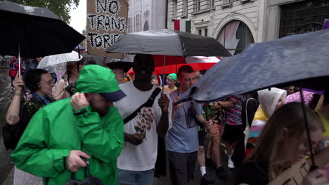 Demonstranten-Halten-Plakate-Und-Regenschirme-Hoch,-Während-Tausende-Zu-Beginn-Des-London-Trans-Pride-2023-Durch-Den-Regen-Marschieren